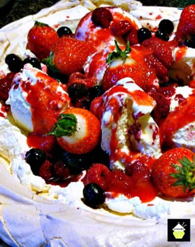 Fruit Pavlova! A delicious, easy dessert with a mix of berries, ice cream, whipped cream sitting in a crisp meringue, and topped off with a fruit ripple sauce.