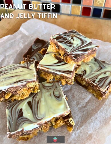 Peanut Butter and Jelly Tiffin is a delicious American twist on the classic British Tiffin chocolate snack, made up of peanut butter, jelly, crushed cookies, chocolate and raisins. An easy no bake sweet chocolate bar recipe.